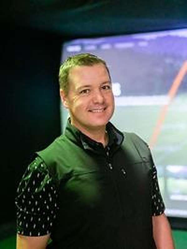Dave Gedris, PGA Professional, in front of a simulator bay at Oakmont Golf Center