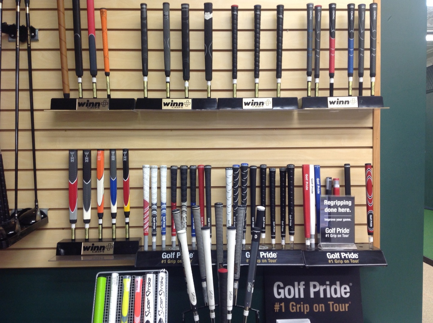 Winn, Golf Pride, and SuperStroke grips displayed on the wall of the Oakmont Golf Center repair shop