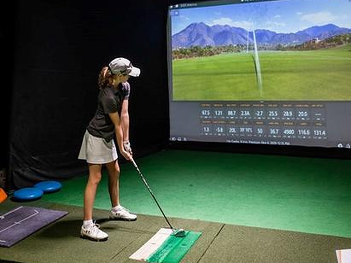 A golfer playing a simulated round on a TrackMan bay at Oakmont Golf Center